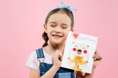 happy child holding greeting card with i love you mom lettering isolated on pinkの写真素材