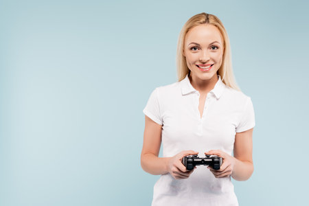 KYIV, UKRAINE - NOVEMBER 25, 2020: happy woman holding joystick isolated on blue