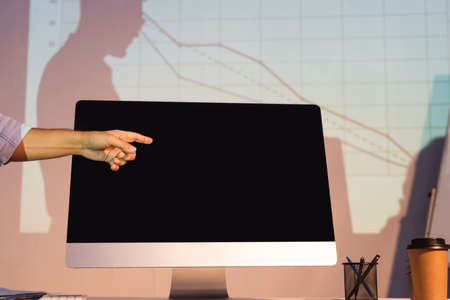 cropped view of businessman pointing with finger at computer monitor with blank screenの写真素材