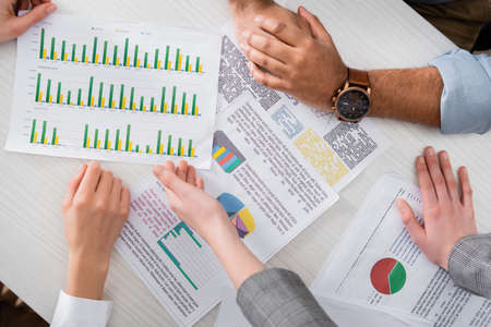 Cropped view of businesspeople analyzing charts on papers