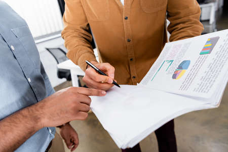 Cropped view of businessman holding pen near papers and colleague pointing with fingerの写真素材