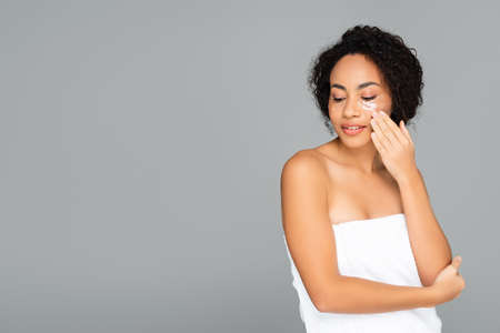 African american woman in towel and eye patches isolated on grayの写真素材