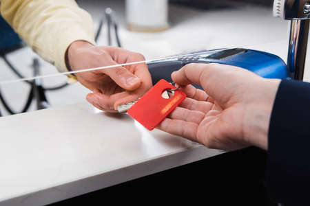 Cropped view of hotel receptionist giving key to man