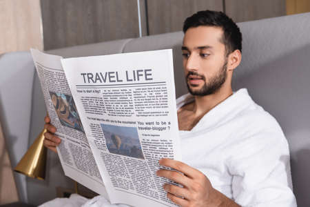 Travel life lettering on newspaper in hands of arabian man in bathrobe in hotelの写真素材