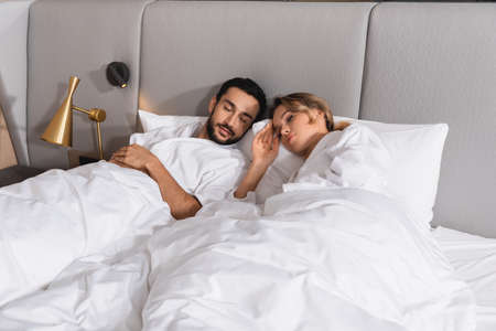 Young interracial couple sleeping on hotel bedの写真素材