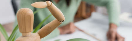 selective focus of wooden human figurine near african american architect on blurred background,...