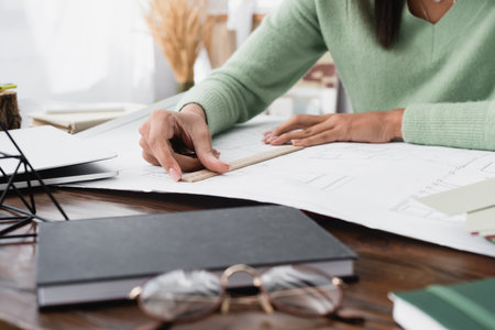 partial view of african american architect measuring blueprint with ruler on blurred foregroundの写真素材