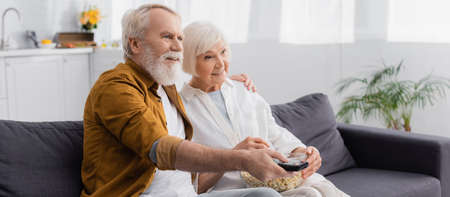 Elderly couple with popcorn watching movie, bannerの写真素材