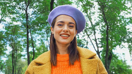 joyful trendy woman smiling at camera in autumn parkの写真素材