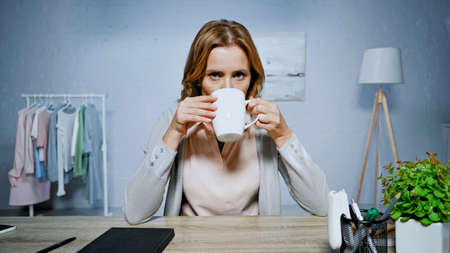 Woman drinking tea and looking at camera at homeの写真素材