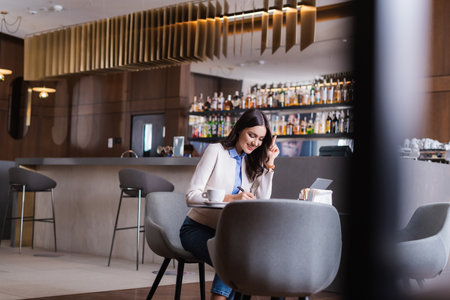 cheerful freelancer showing idea gesture while working in restaurant, blurred foregroundの写真素材