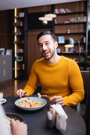 Cheerful arabian man dinning with girlfriend on blurred foreground in modern restaurantの写真素材
