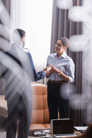 Smiling businesswoman looking at partner near laptops during meeting in restaurantの写真素材