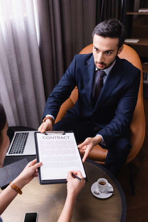 Businesswoman singing contract near arabian businessman in restaurantの写真素材