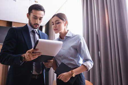 Multiethnic business people with clipboard and notebook in restaurant