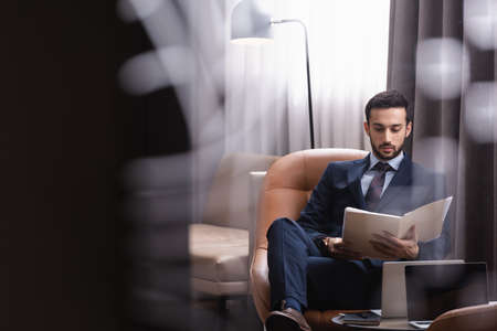 Muslim businessman in formal wear looking at paper folder in restaurantの写真素材