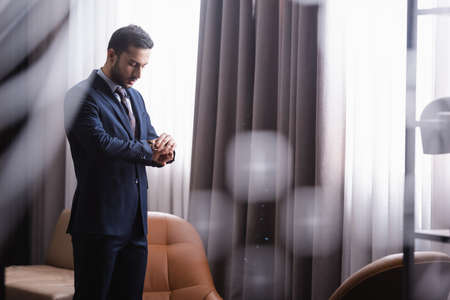 Arabian businessman looking at wristwatch in restaurant