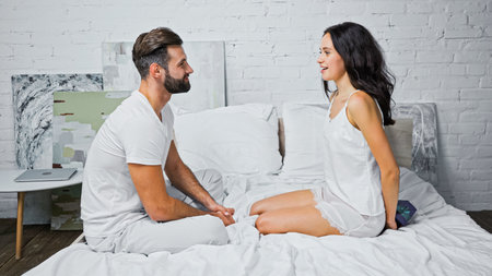 side view of brunette woman holding valentines day present behind back near boyfriend in bedroom