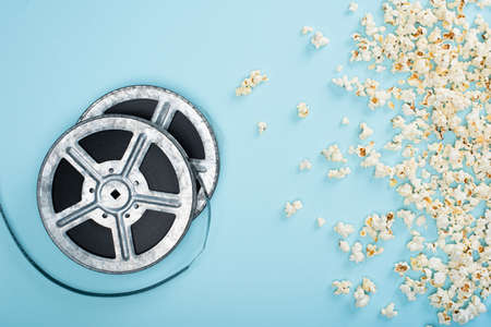 top view of film reels near scattered popcorn on blue, cinema conceptの写真素材