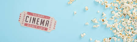 top view of cinema ticket and crispy popcorn on blue, bannerの写真素材