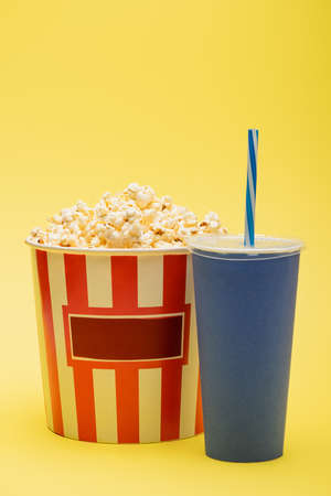 cup of soda near bucket full of tasty popcorn on yellow, cinema conceptの写真素材