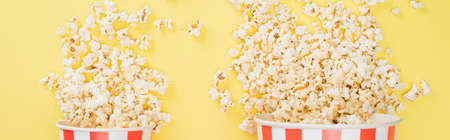 top view of big and small buckets with crunchy popcorn on yellow, banner, cinema conceptの写真素材