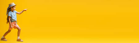 full length of kid with temporary tattoo on hand pointing with finger on yellow, bannerの写真素材