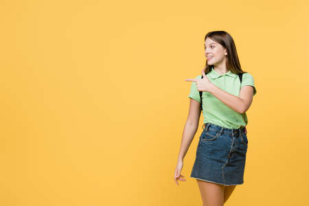 Cheerful teenager pointing with finger isolated on yellow