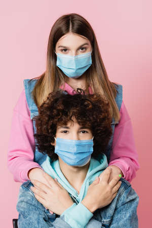 Girl in medical mask holding hands of boyfriend isolated on pinkの写真素材