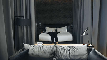 businesswoman in formal wear lying on bed in hotel roomの写真素材
