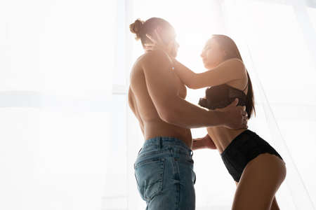 Low angle view of sexy couple touching each other near windowの写真素材