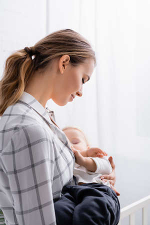 young smiling woman lulling child at home
