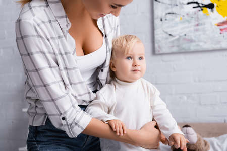 smiling mother hugging little son looking away at homeの写真素材