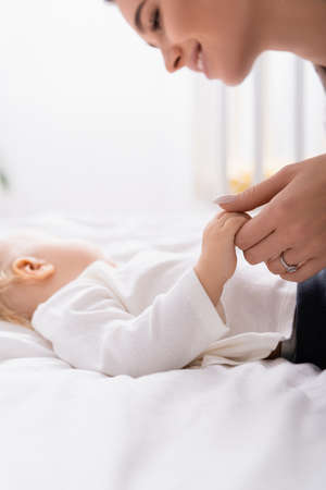 happy mother holding hand of little child sleeping at home, blurred background