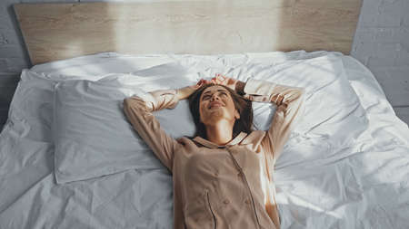 happy young woman smiling and lying on bedの写真素材