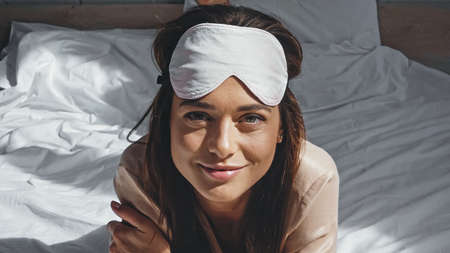 sunlight on smiling woman in eye mask looking at camera