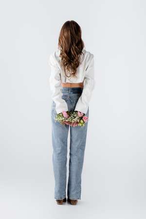 Back view of woman with flowers in sleeves of jacket standing on gray backgroundの写真素材