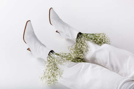 Cropped view of legs of woman in white shoes and pants with flowers on gray backgroundの写真素材