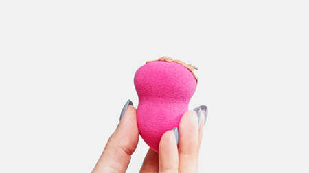 cropped view of woman holding beauty blender sponge with makeup foundation isolated on whiteの写真素材