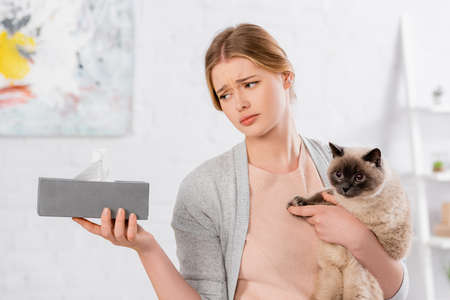 Sad woman holding siamese cat and box with napkinの写真素材
