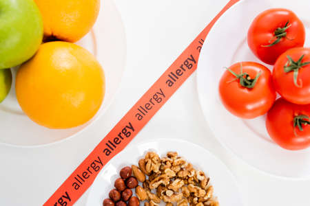 Top view of ribbon with allergy lettering near fruits, tomatoes and nutsの写真素材
