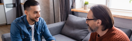 smiling hispanic man talking to father at home, bannerの写真素材