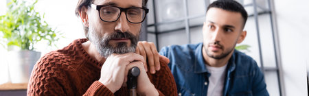 young hispanic man touching shoulder of offended father, blurred background, banner
