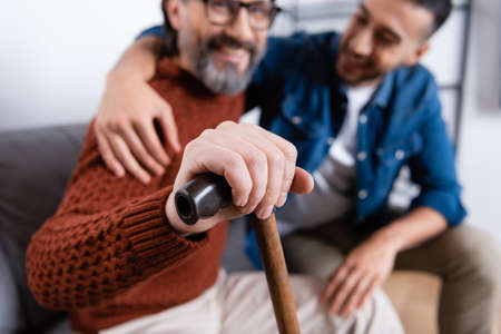selective focus of happy man with walking stick near young hispanic son, blurred backgroundの写真素材