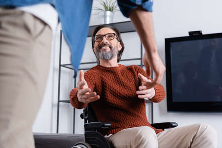 happy handicapped man meeting son with outstretched hands, blurred foregroundの写真素材