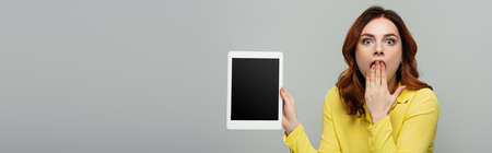 amazed woman holding digital tablet with blank screen isolated on gray, bannerの写真素材