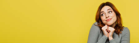 young woman with clenched fists looking away isolated on yellow, bannerの写真素材