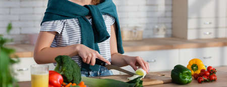 partial view of woman preparing vegetable breakfast in kitchen on blurred foreground, bannerの写真素材