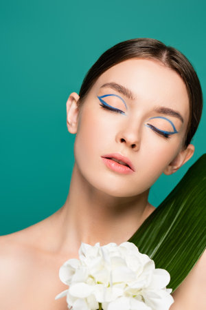 portrait of charming woman with closed eyes near white peony and green leaf isolated on greenの写真素材