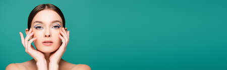 young sensual woman touching face while looking at camera isolated on green, banner